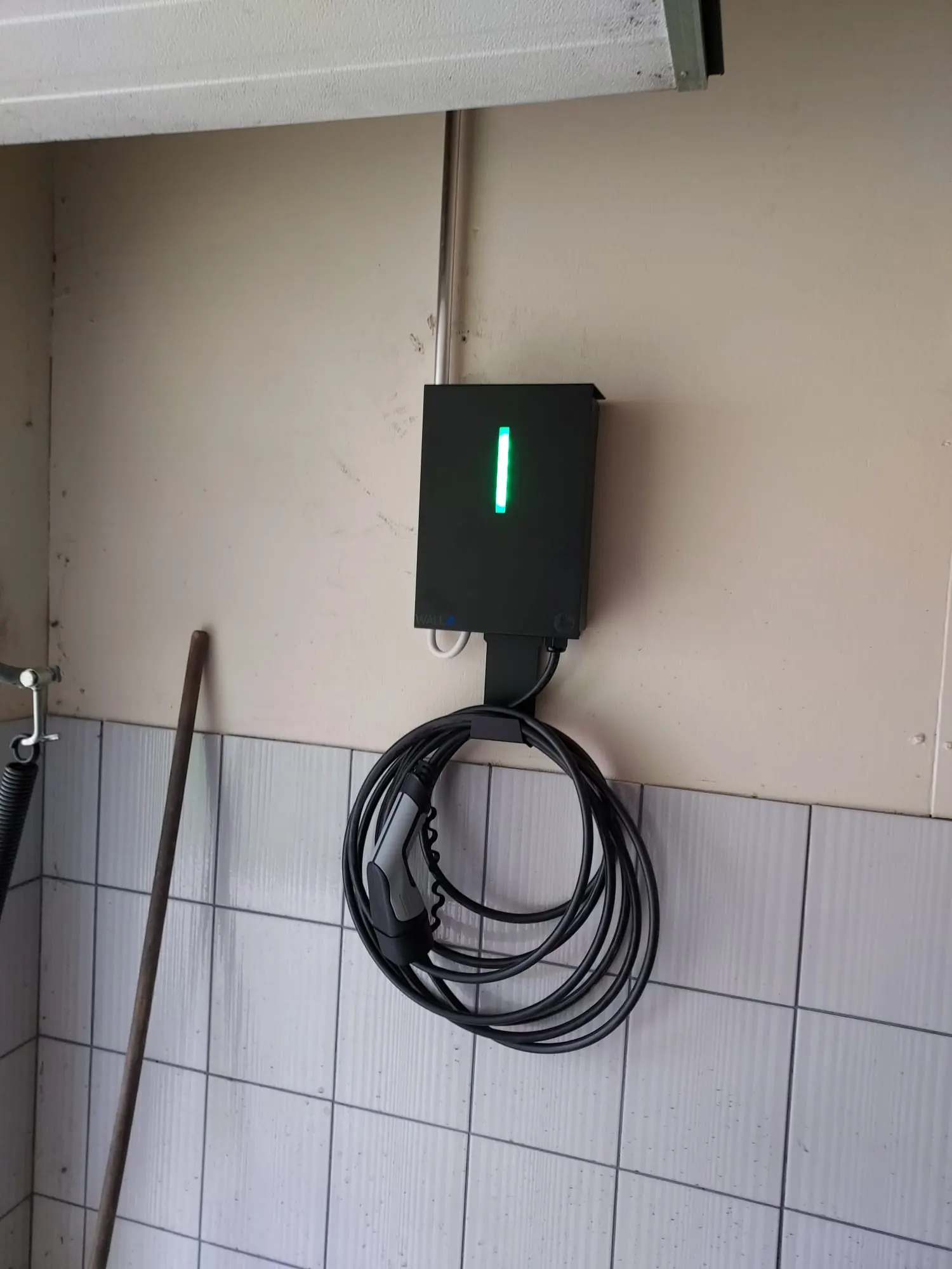Seinään asennettu latausasema autotallissa